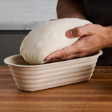 A baker’s hands lifting dough from a batard banneton.